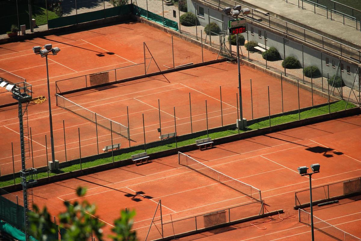 Aerial view of red clay tennis courts edged by trees